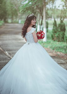 Woman in White Wedding Dress Holding Red Bouquet