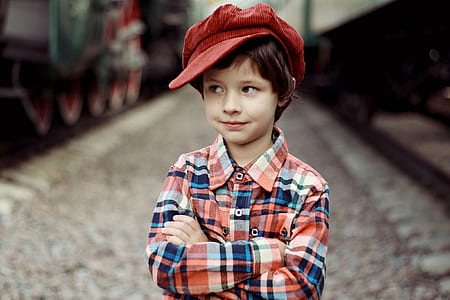 standing boy in plaid long-sleeved shirt with red newsboy hat