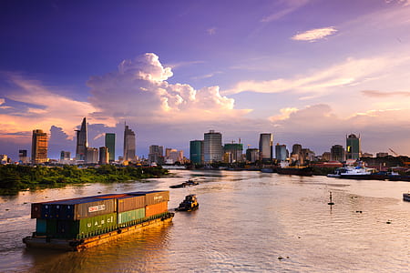 cargo vessel with intermodal containers on body of water near high-rise buildings