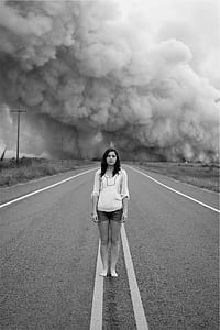 grayscale photo of woman standing on road