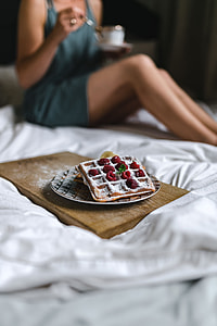 Breakfast in bed - waffles with raspberries and cup of coffee on the tray