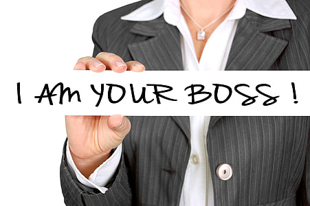 woman wearing grey blazer holding i am your boss! sign