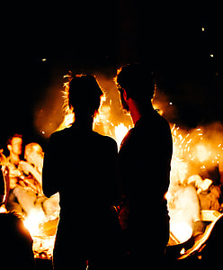 silhouette of man and woman while watching fire during night time