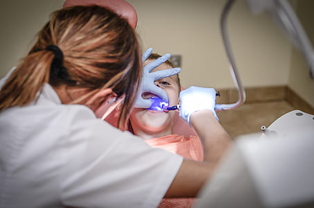 woman wearing scrub shirt checking up girl's teeth