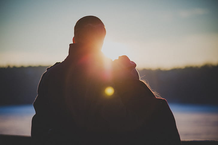 silhouette of couple facing body of water