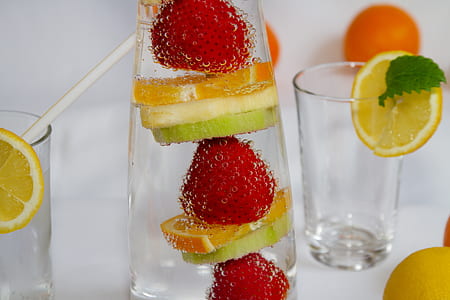 orange, strawberry, and lemon juice with drinking glasses