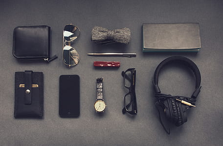black headphones, black framed eyeglasses, black smartphone, black leather card wallet
