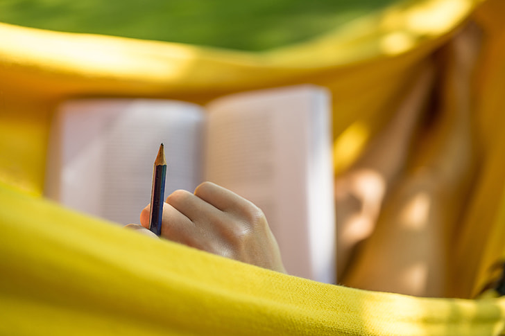 Woman studying and reading with pencil in garden