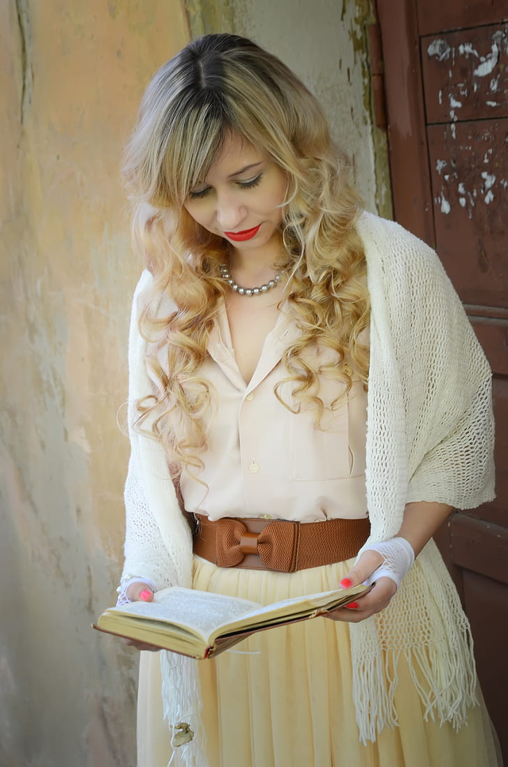 woman wearing white knitted headscarf and beige bow-accent dress holding book