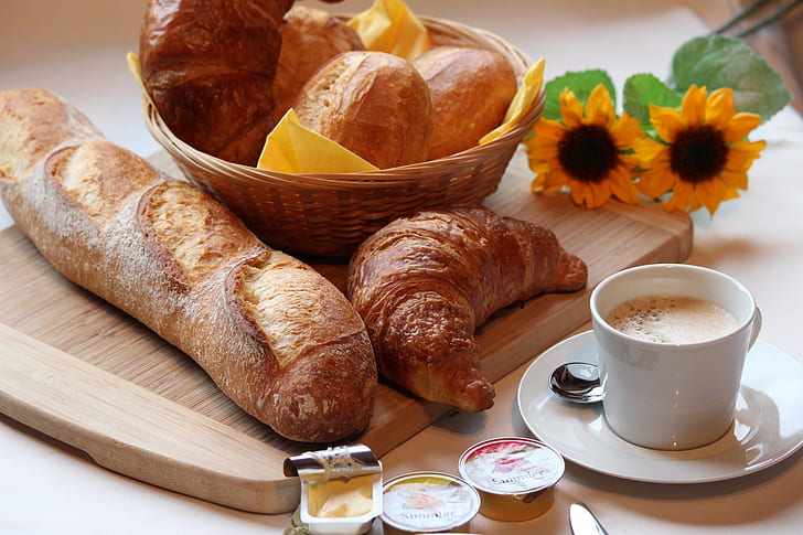 french bread, croissant, butter, and cup of coffee on brown wooden table