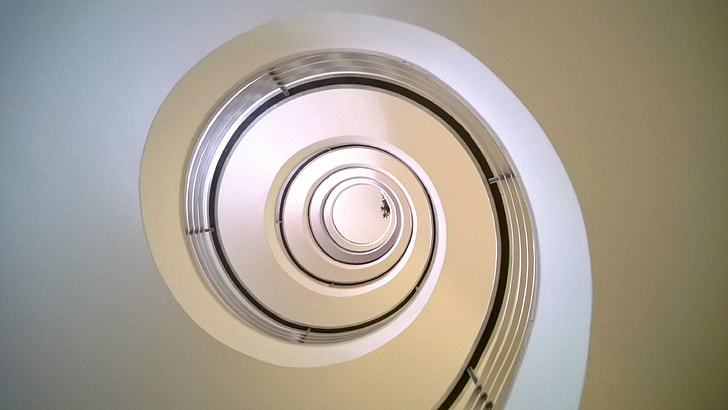 bottom view of white concrete spiral staircase