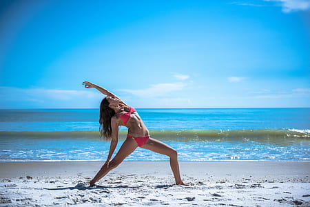 photo of woman doing yoga on the beach