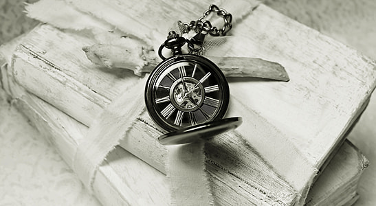 silver pocket watch on white books