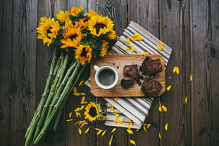 sun flower on wooden board beside coffee cup and grilled meat