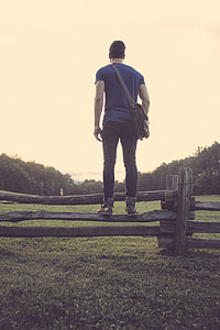 man standing on wooden fence
