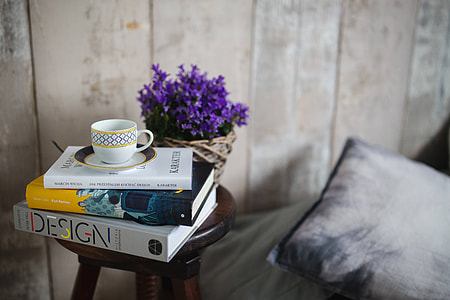 Books and purple flowers on a wooden stool by the bed