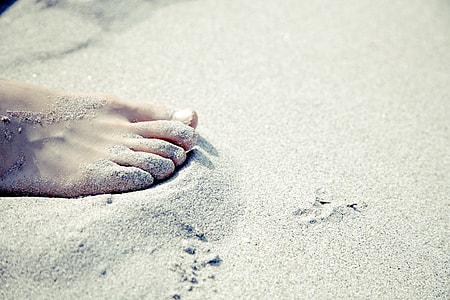 photo of right human foot on white sand