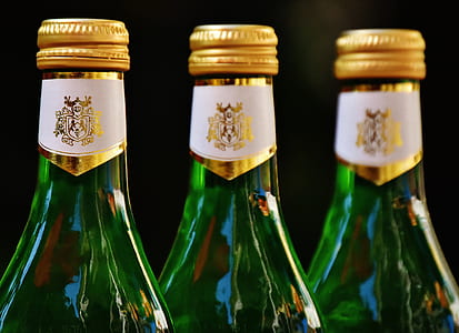 three green glass bottles with yellow bottle caps