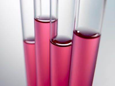 four clear vials with pink liquids