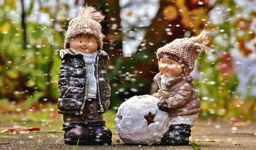 boy in black coat beside woman in brown coat holding snowball figurines wallpaper