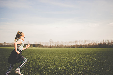 girl running in the grass field during daytime