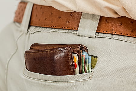 person wearing gray denim bottoms with brown leather wallet