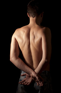 topless man showing his back and wearing gray denim bottom with both his hands cross on his back