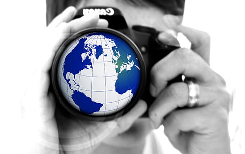 selective color photography of man holding earth globe camera
