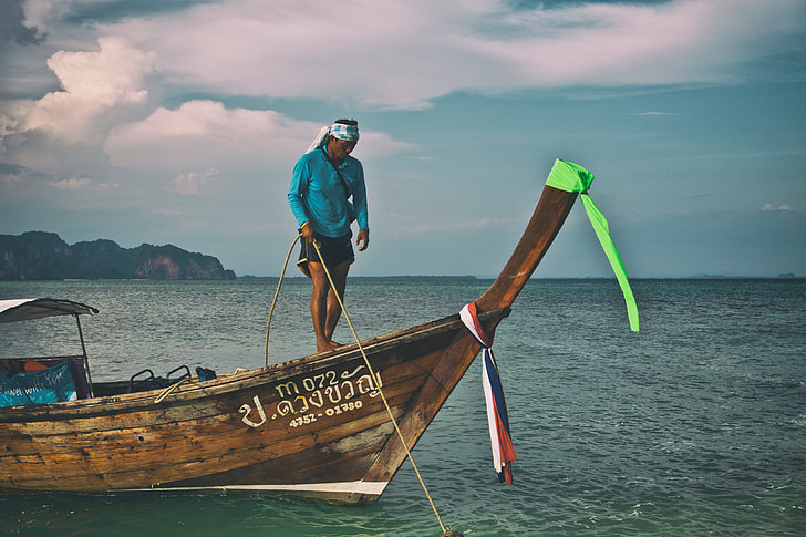 A man secures a longtail boat with rope in the Krabi district of Thailand
