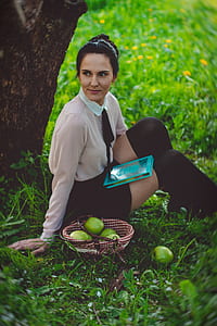 Woman Weasring White Dress Shirt Sitting in Green Grass Under Brown Large Tree