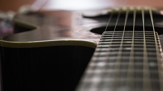 shallow focus photography of brown and black acoustic guitar