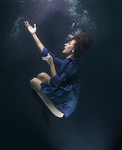 photo of woman underwater bending knees