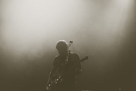 man playing guitar in sepia photography
