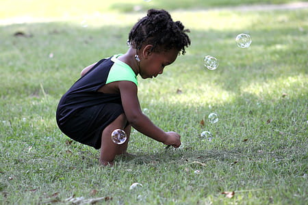 girl playing bubbles on green grass field