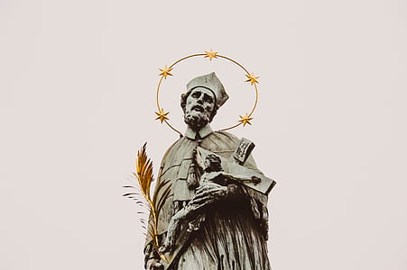statue of man holding crucifix of Jesus Christ
