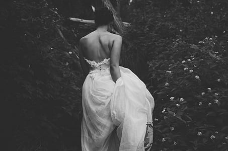 grayscale photography of woman with wedding dress near plants
