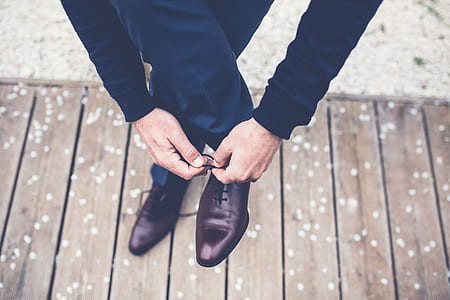 man lacing up his brown leather oxford shoe on the right side