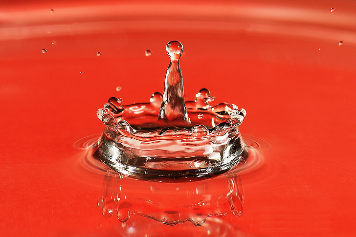 Closeup shot of a water drop splash on red background