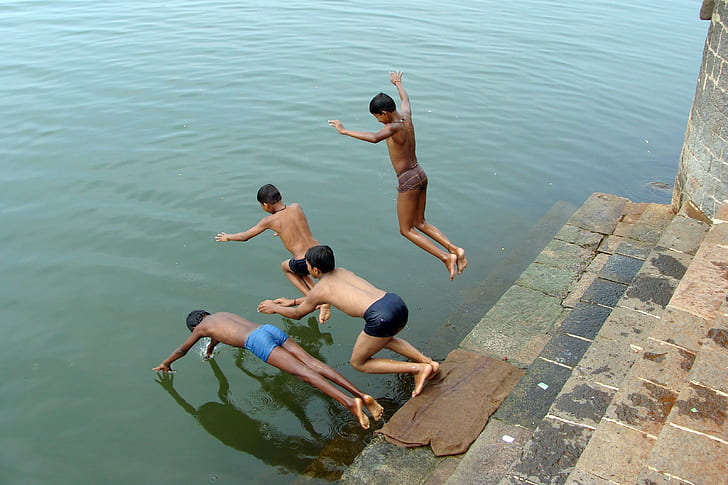 boys diving in water during daytime