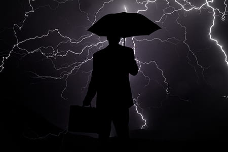 silhouette of man holding briefcase and umbrella