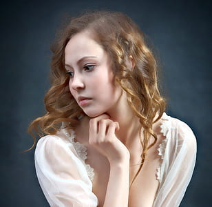 woman in white top pose for photo while hand on her neck