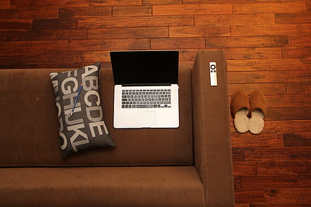 silver MacBook on brown couch