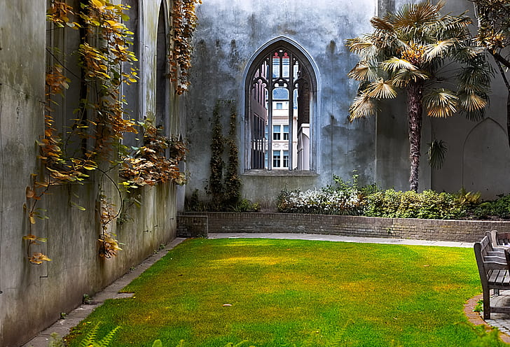 green and yellow lawn beside gray concrete walls with plants at daytime