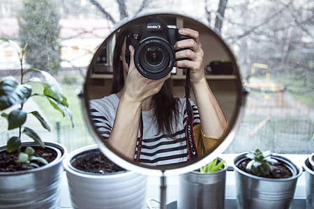 pedestal mirror showing woman playing DSLR camera