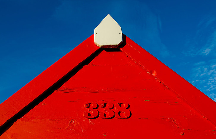 A red coastal hut contrasts against a blue sky