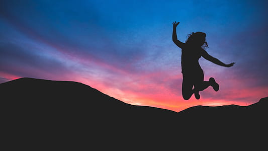 silhouette photo of woman jumping against the mountain