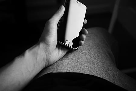 grayscale photo of person holding iPhone