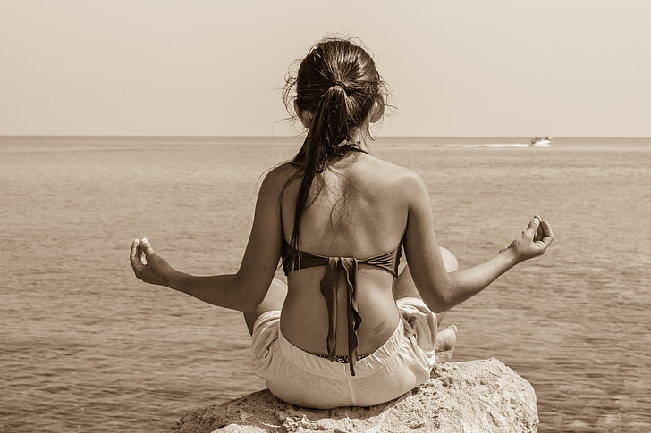 meditating woman sitting on rock