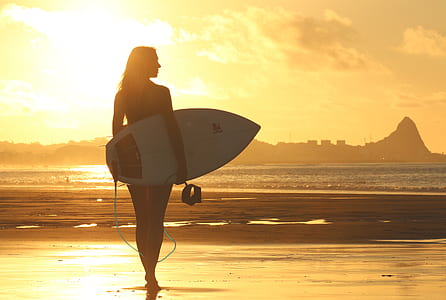 silhouette photography of woman holding surfboard