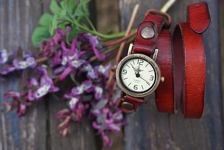 round gold-colored analog watch with red leather strap